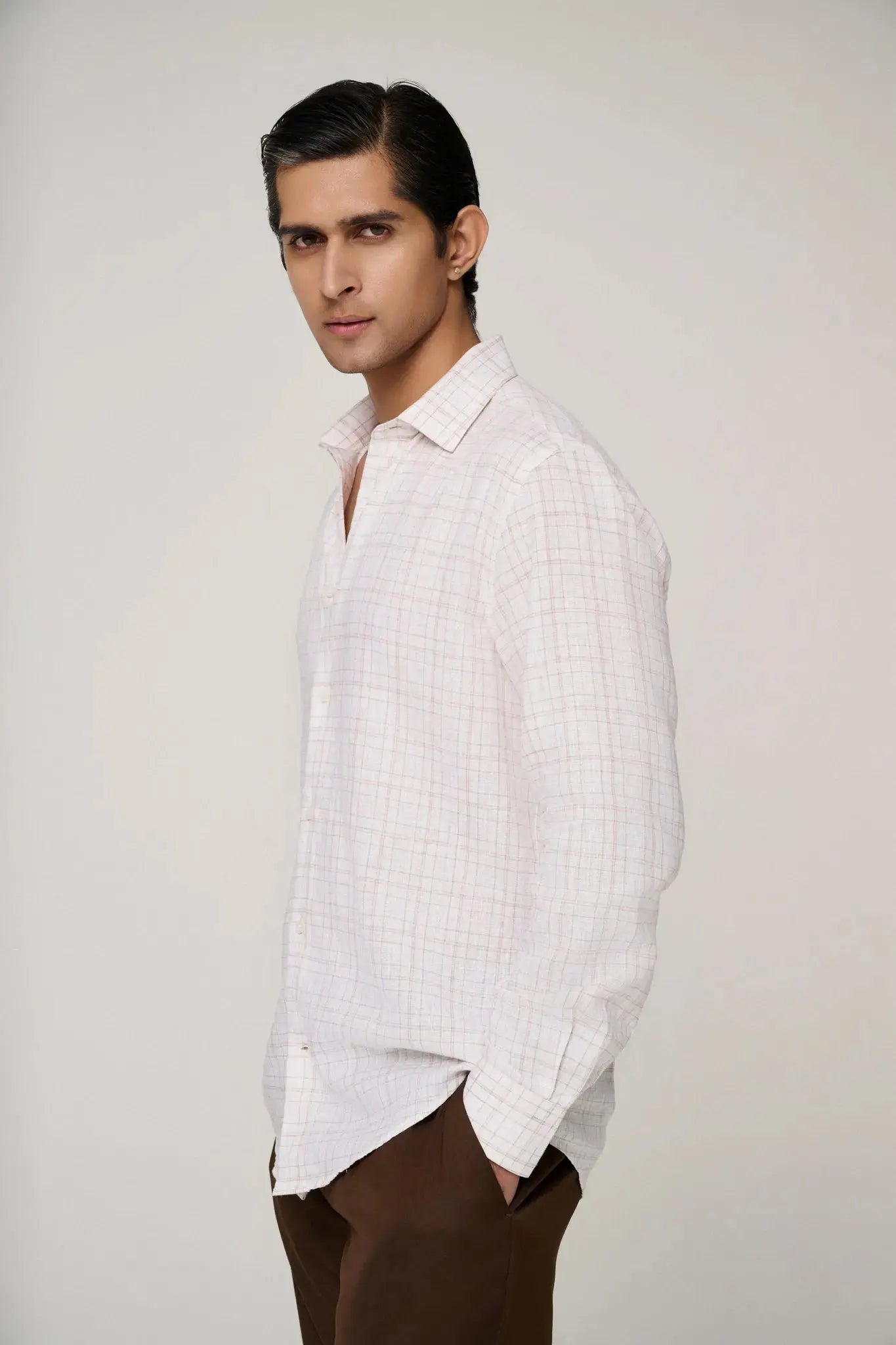 Side profile of model in pink check linen shirt, showcasing fit.