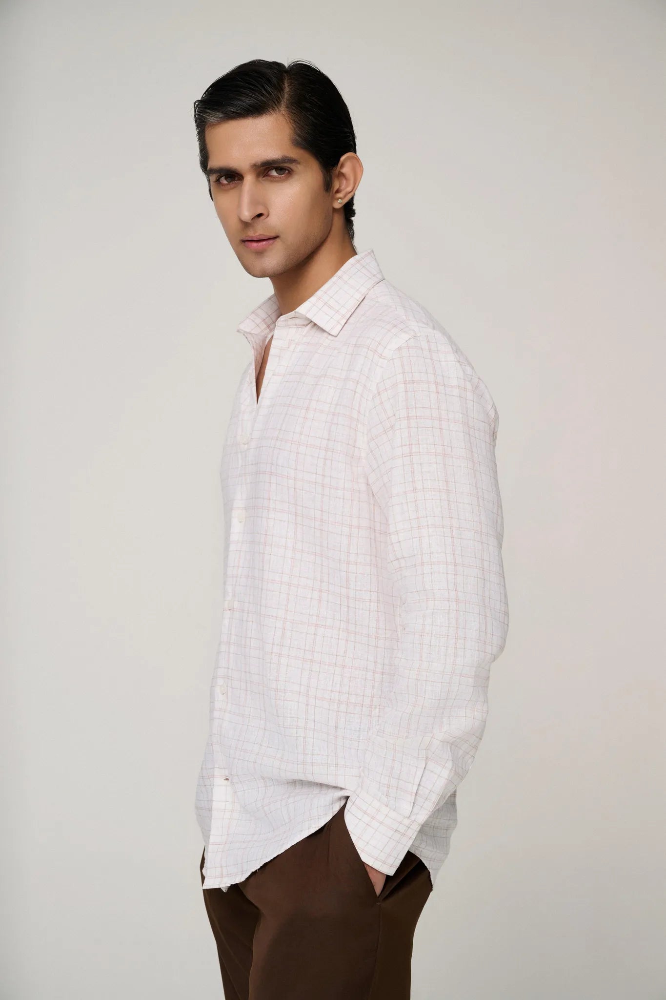 Side profile of model in pink check linen shirt, showcasing fit.