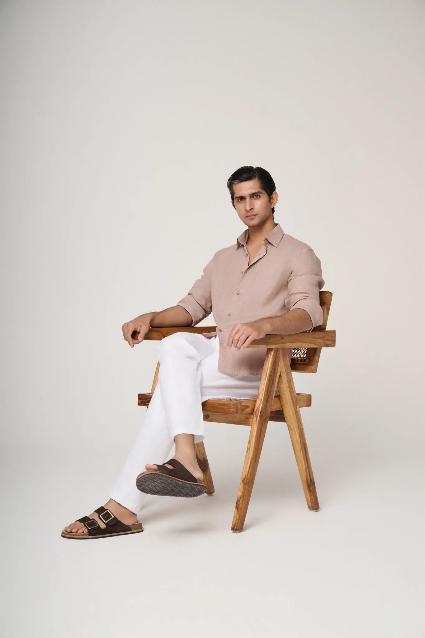 side profile of a seated model wearing a camel linen shirt